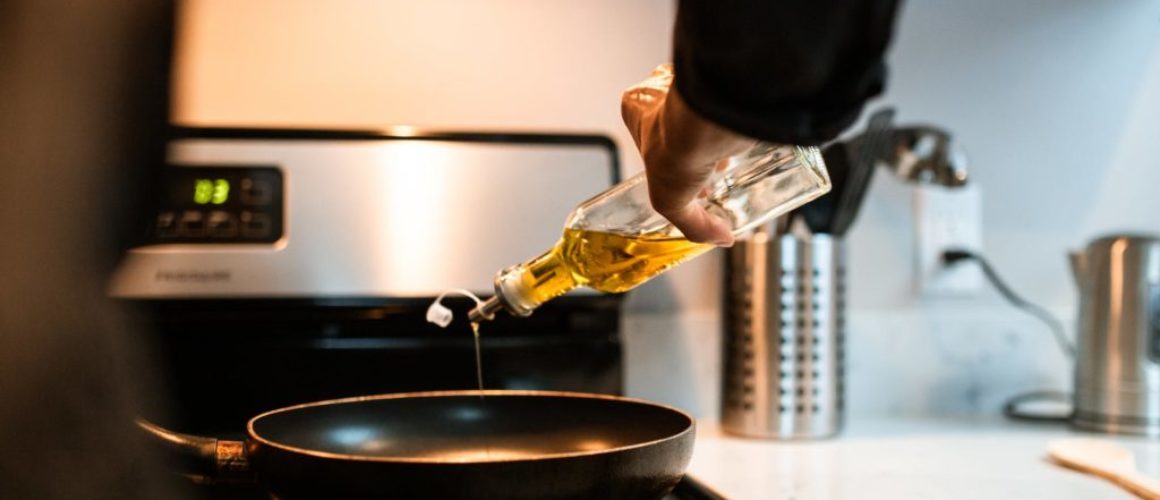 crop faceless chef pouring oil in pan