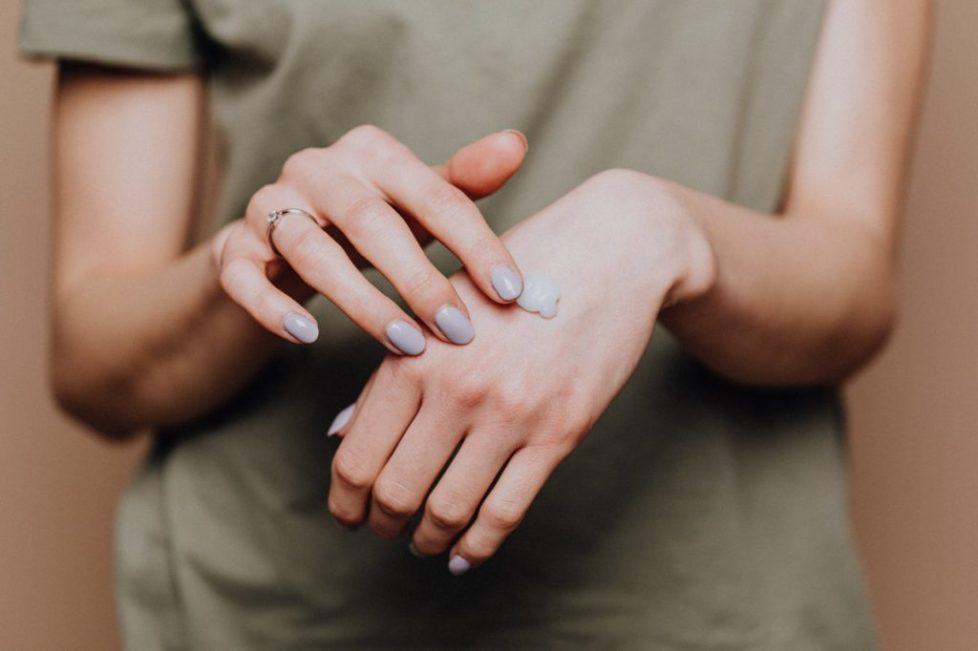 crop woman applying cream on hands