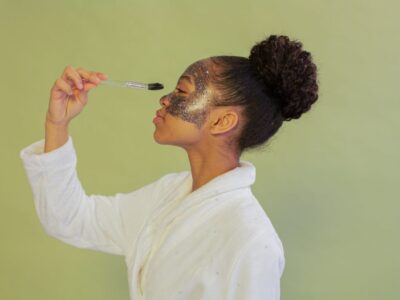 black woman applying facial mask with brush