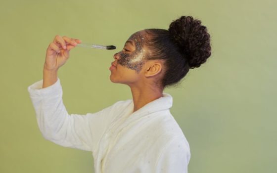 black woman applying facial mask with brush